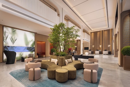 A spacious lobby with a central seating area, a large screen, and a reception desk.. Hilton Garden Inn Jinghe County