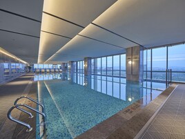 Piscina interior con amplias vistas de la ciudad a través de grandes ventanales.