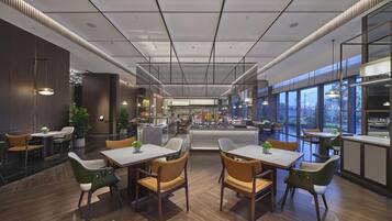 A modern restaurant with wooden flooring, multiple seating areas, and large windows offering views.