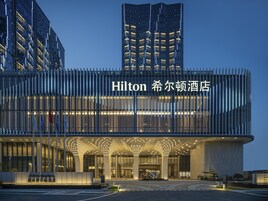 Un moderno edificio de hotel con señalización iluminada y una entrada destacada.