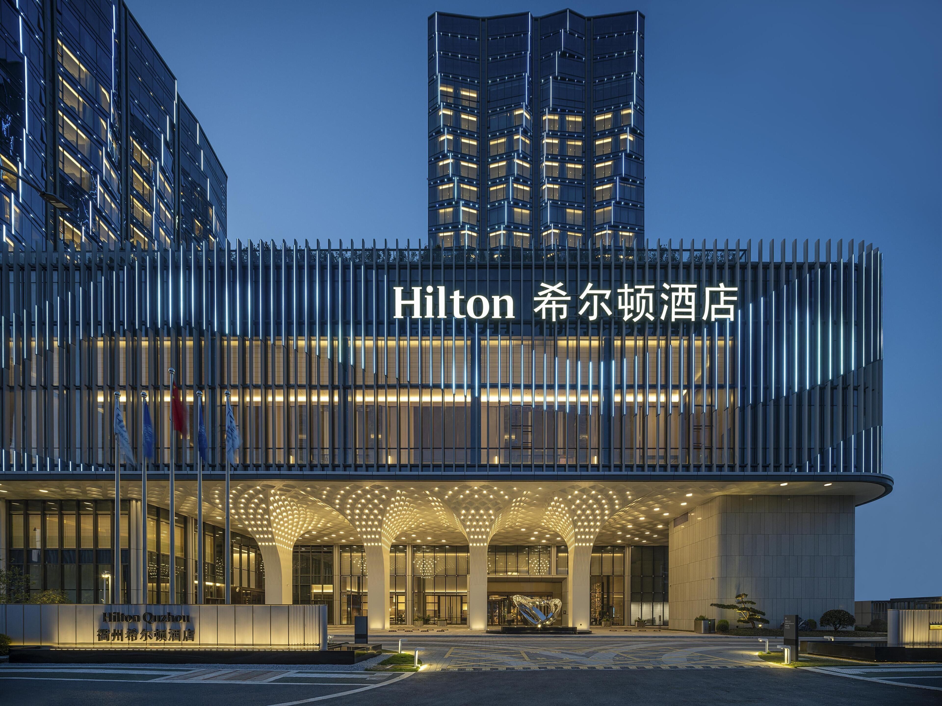 A modern hotel building with a prominent entrance, large windows, and a distinctive architectural design.