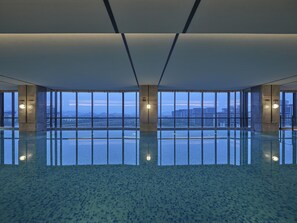 A spacious indoor area with a large reflective floor, large windows offering a view of the cityscape, and a modern architectural design.