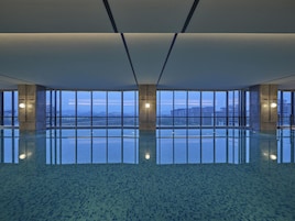 Un espacio interior amplio con un piso reflectante, ventanas grandes que ofrecen vistas panorámicas de la ciudad y un diseño arquitectónico moderno.