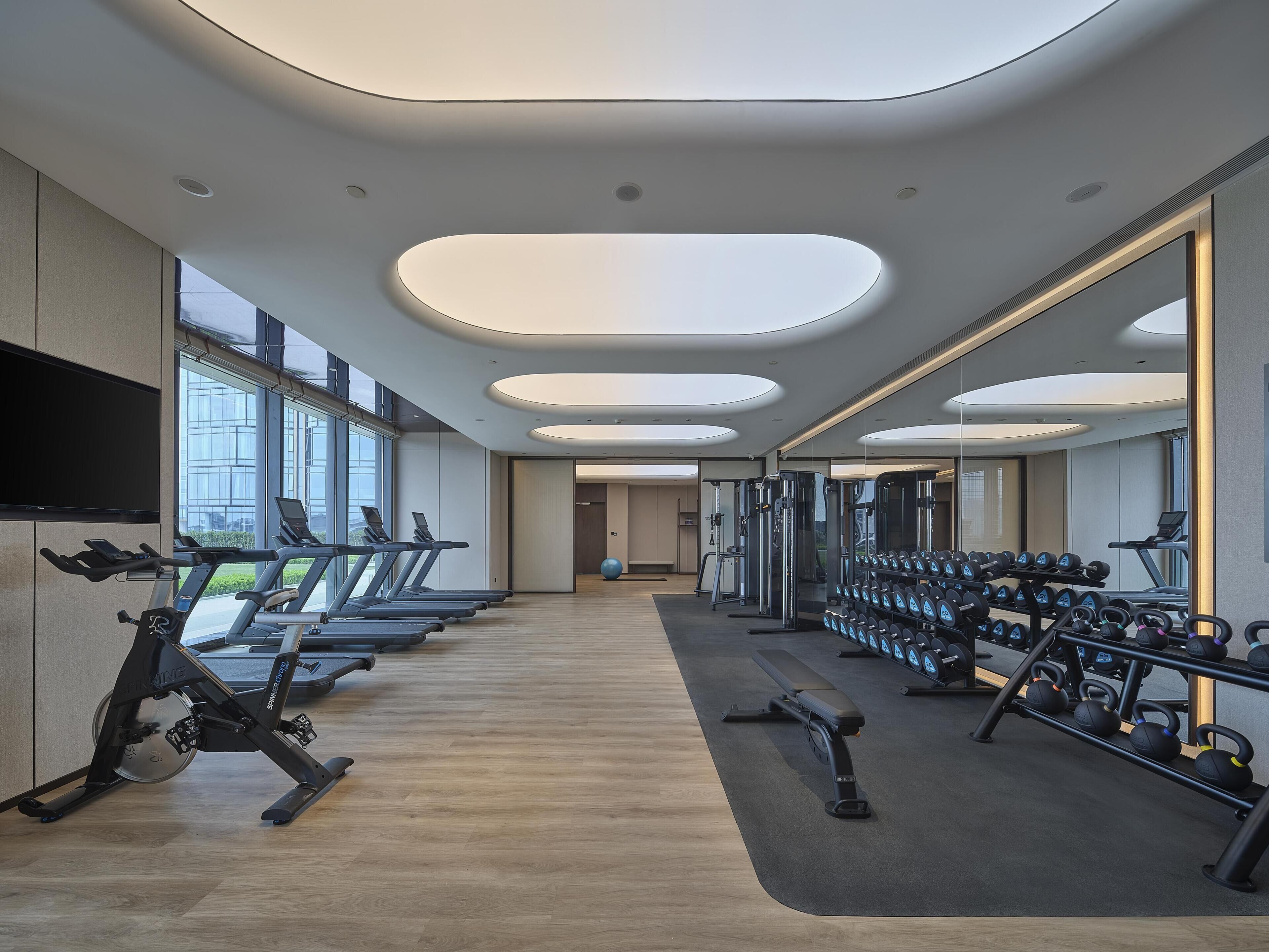 A modern gym with treadmills, weight machines, and kettlebells.
