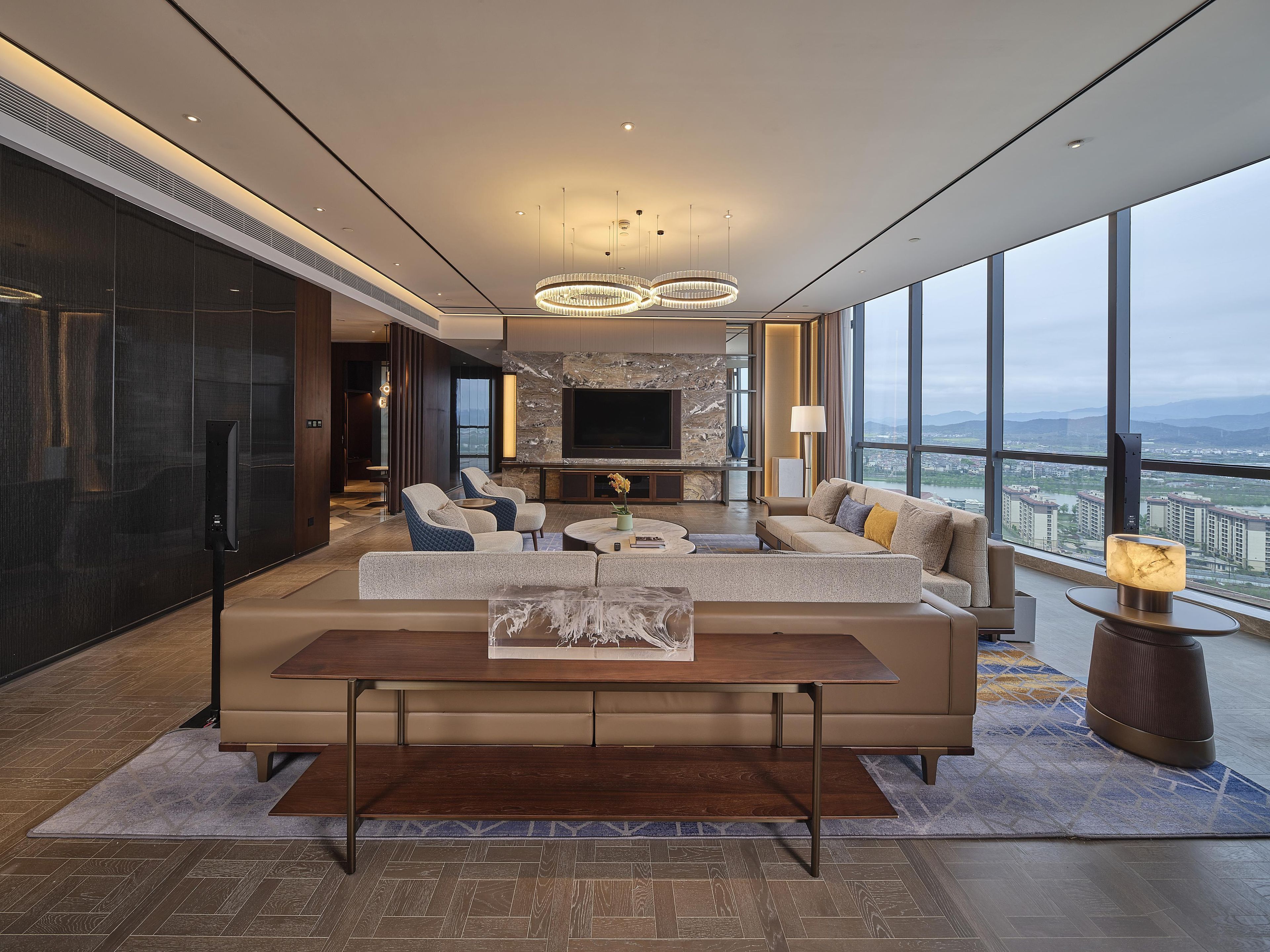 Una sala de estar moderna con un televisor grande, asientos cómodos y vistas a la ciudad.