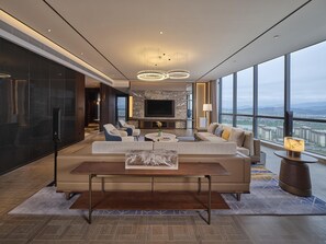 A modern living room with a large TV, comfortable seating, and a city view.