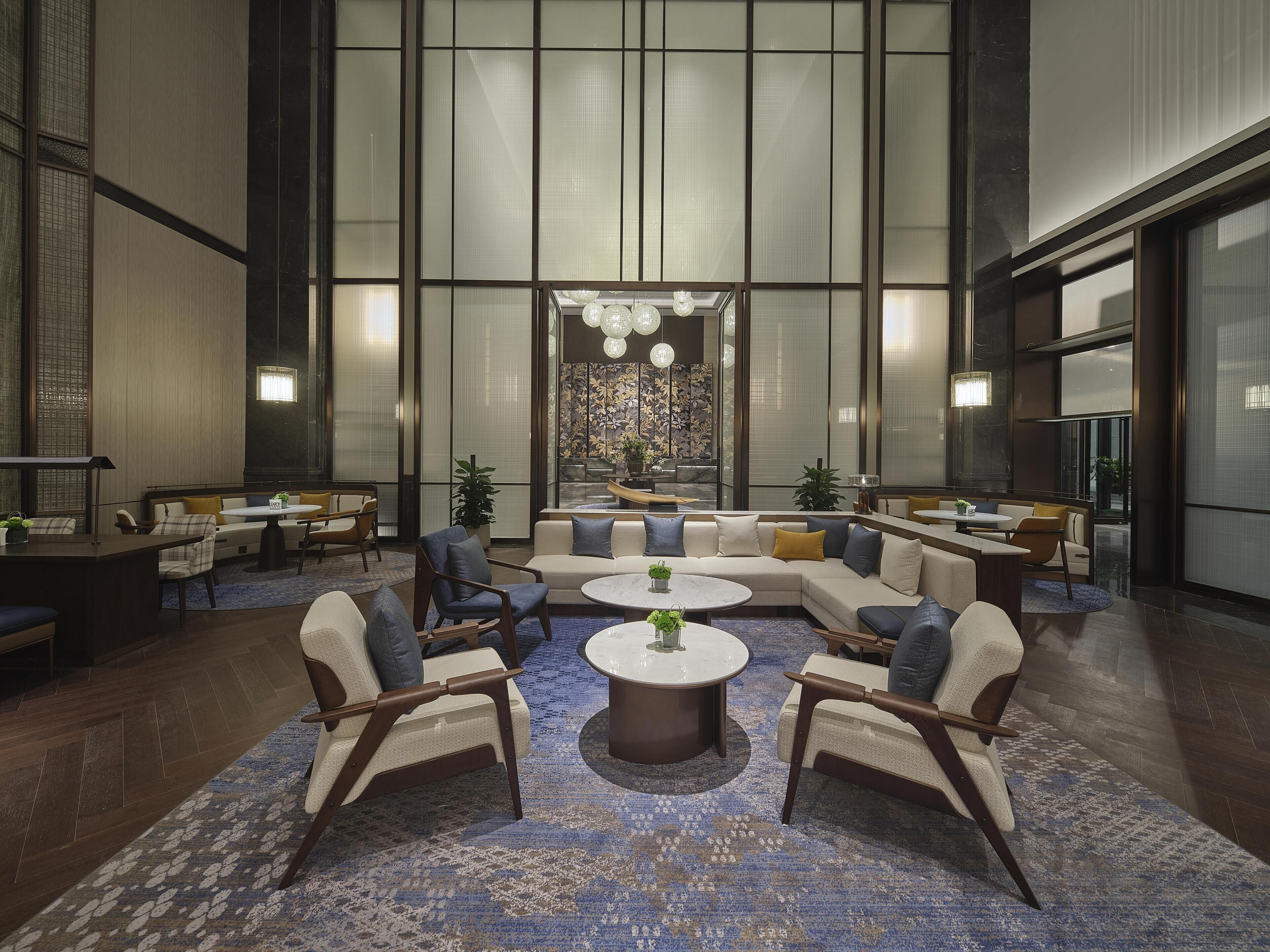 A spacious lobby with a large seating area, a central decorative wall, and a view of the outdoors.
