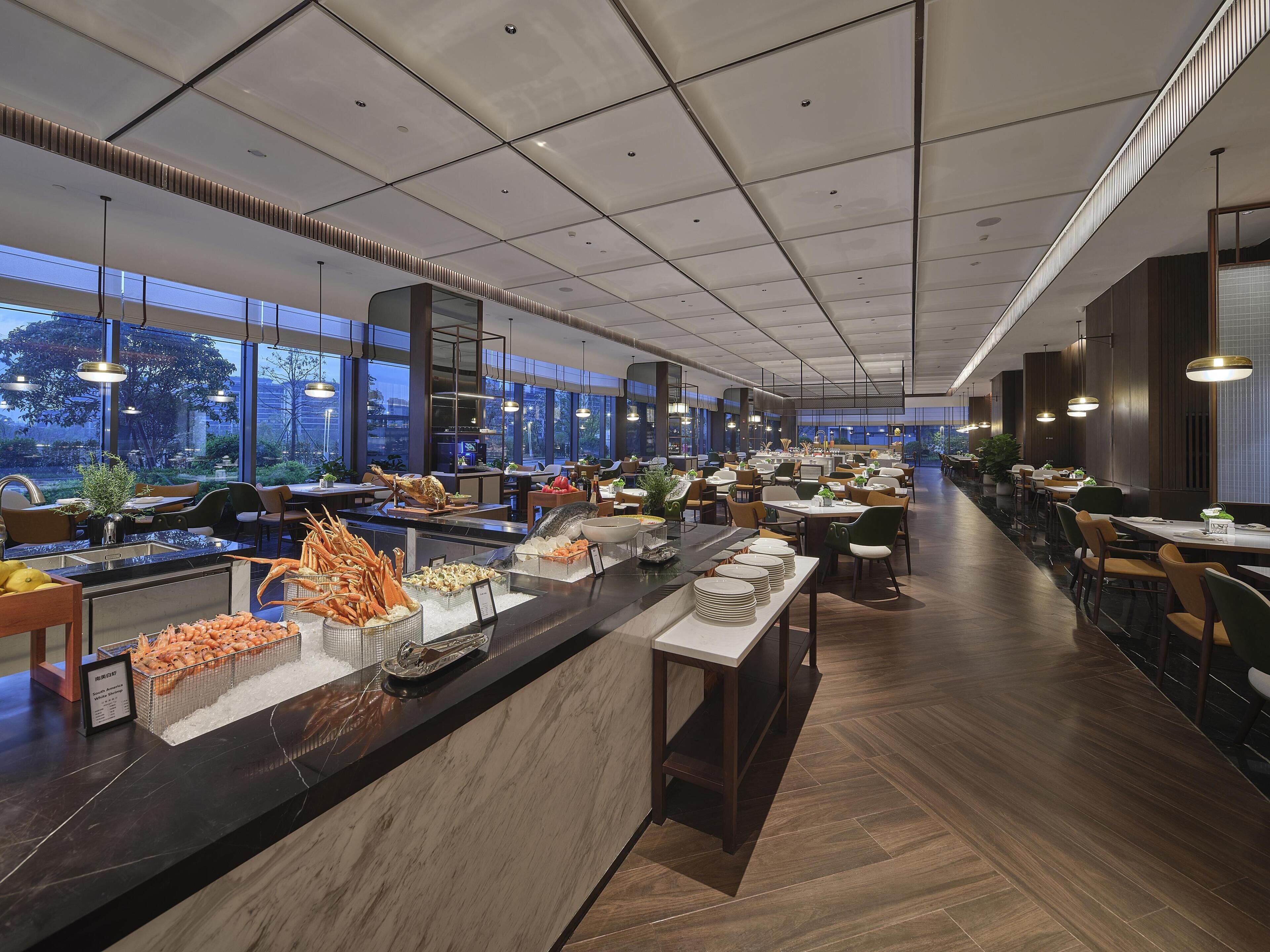 A spacious restaurant with a long counter, multiple dining tables, and a view of the outdoors.