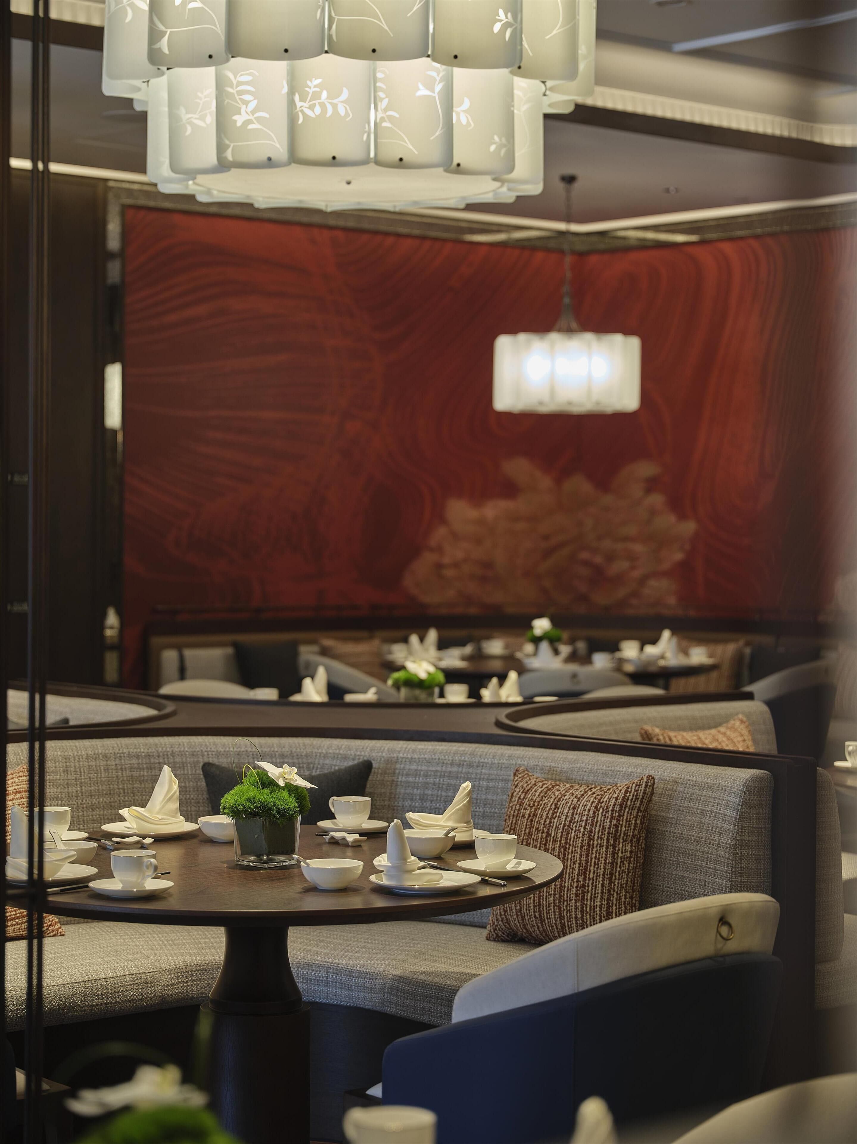 Un restaurante con una decoración moderna, que incluye una pared de madera, asientos acolchados y una araña.