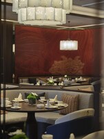 Un restaurante con una decoración moderna, que incluye una pared de madera, asientos acolchados y una araña.