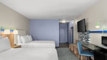 Una camera d'albergo con due letti, una scrivania, una sedia, un televisore e una porta che dà su un'altra stanza.