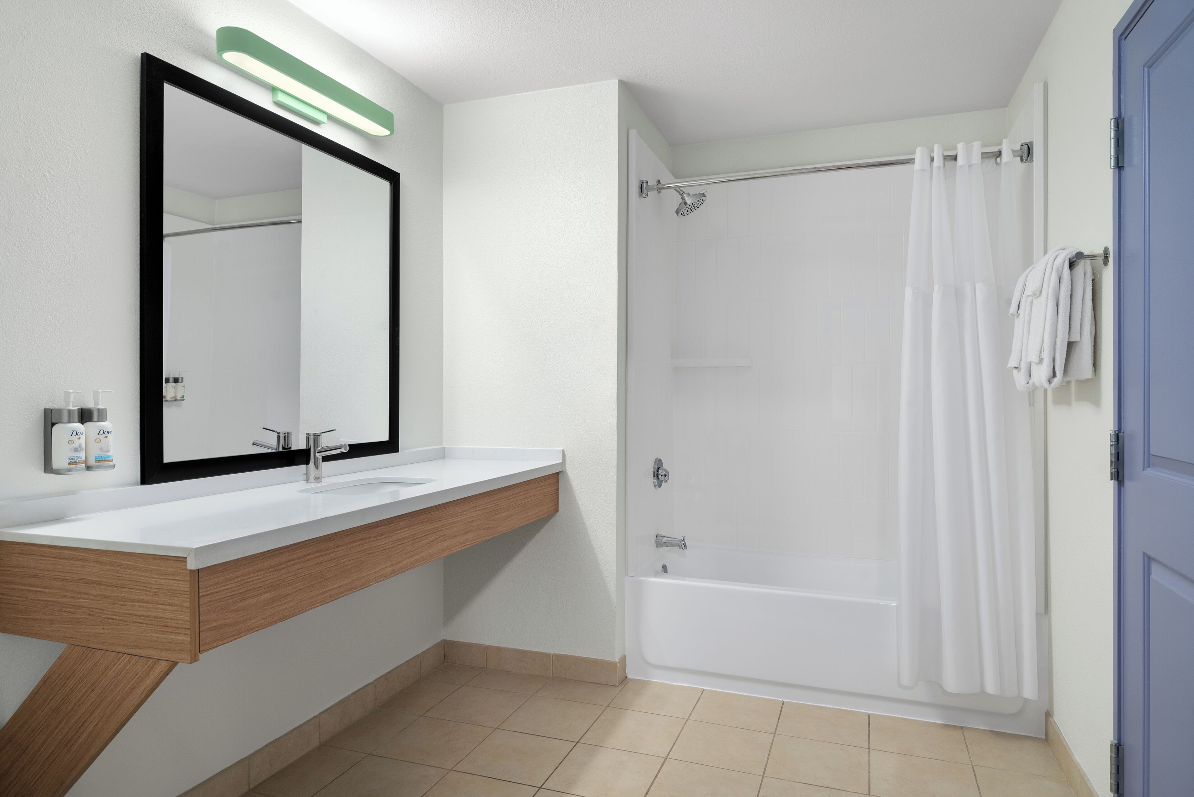 A bathroom with a white sink, a mirror, a shower, and a blue door.