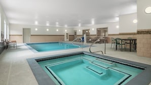 An indoor swimming pool with two separate sections, a lounge area with chairs, and a small table. - Garner Hotel Madison Huntsville Airport by IHG (Madison)