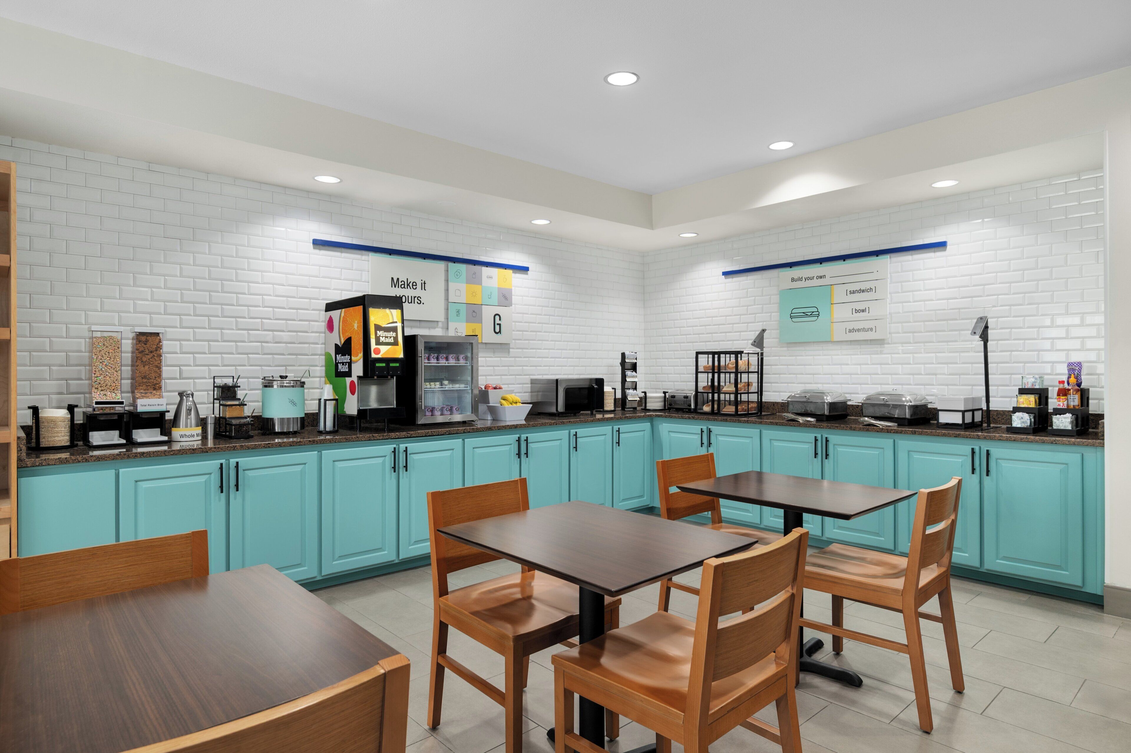 Una cocina moderna con armarios azul verdoso, una cafetera y una mesa con sillas.
