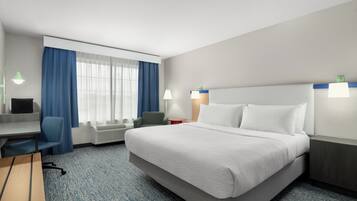 Habitación de hotel con cama, escritorio, silla y dos lámparas de noche.