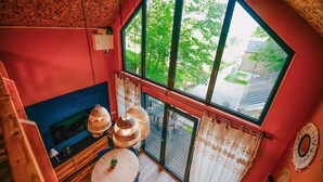 A room with a large window, a fireplace, and a view of greenery outside.