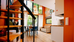 A modern interior with a staircase, dining area, sofa, and kitchen.