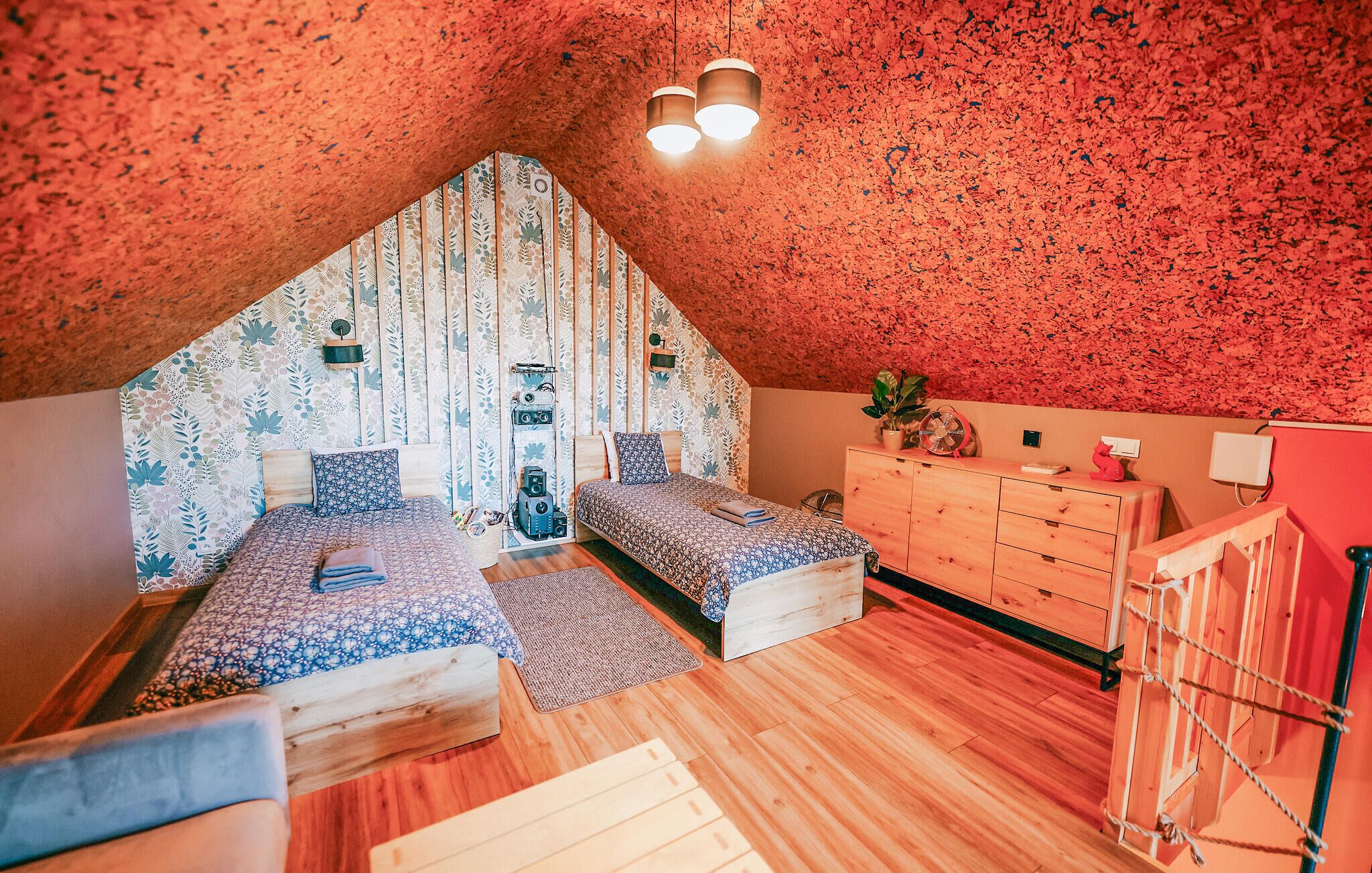 A bedroom with two beds, a dresser, and a ceiling fan.