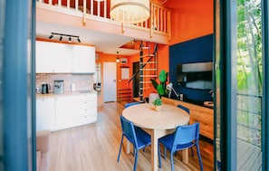 A modern kitchen with white cabinets, a coffee machine, and a dining area with a round table and blue chairs.