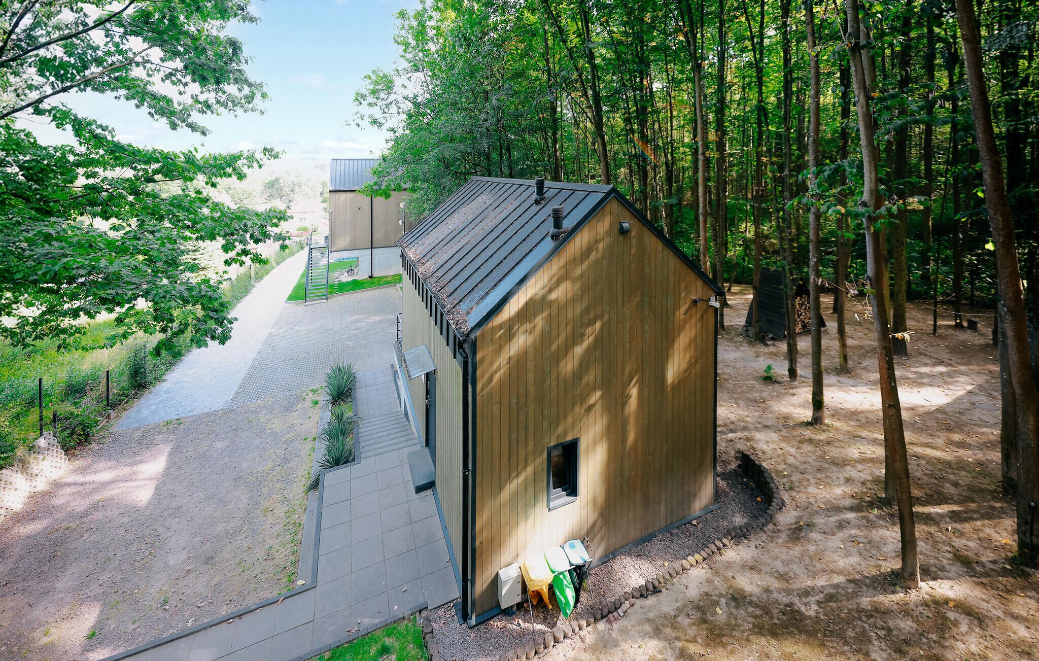 A wooden cabin with a sloped roof, surrounded by a forest.