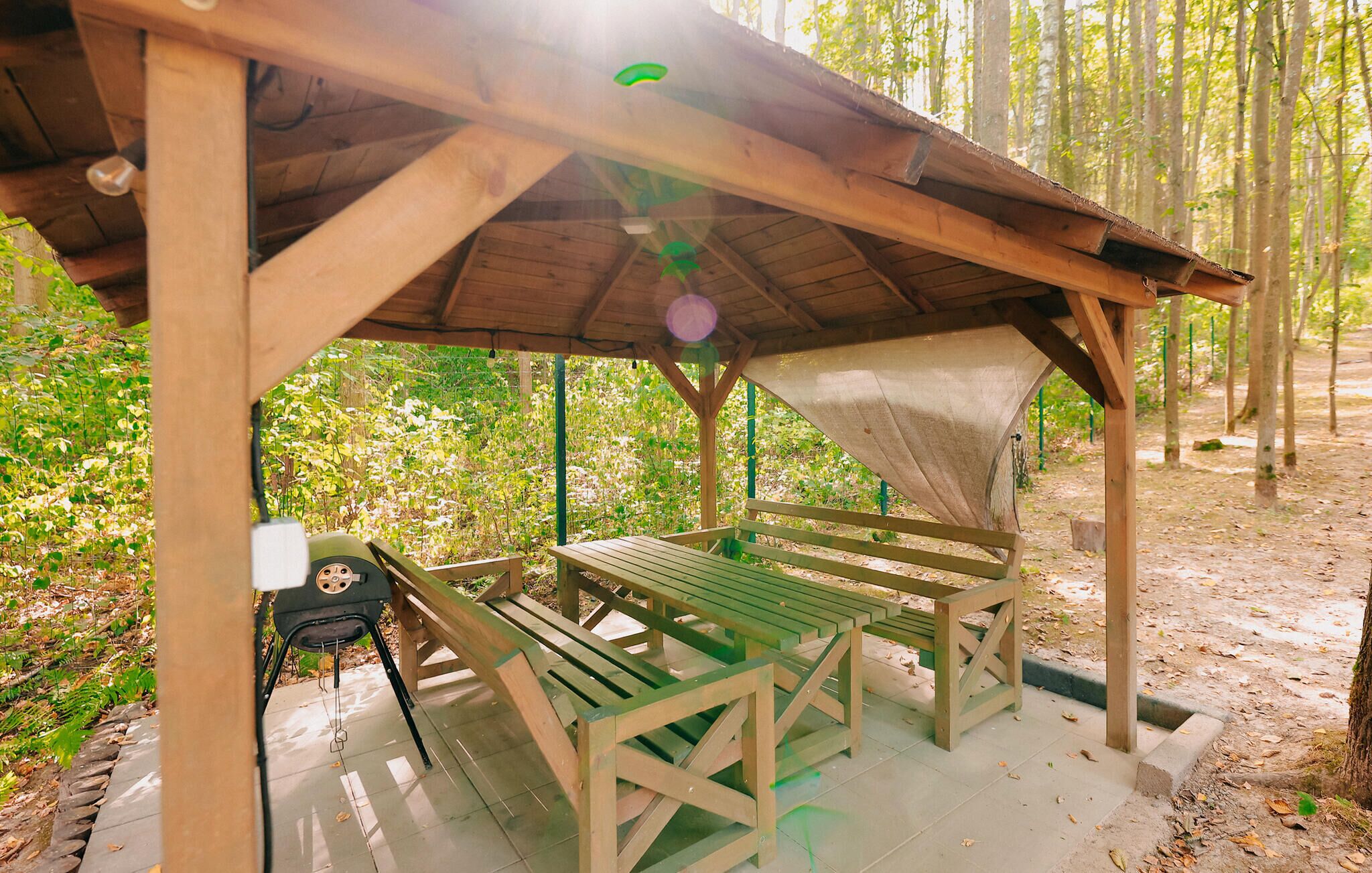 Un espace pique-nique abrité, équipé de bancs et d’un barbecue.