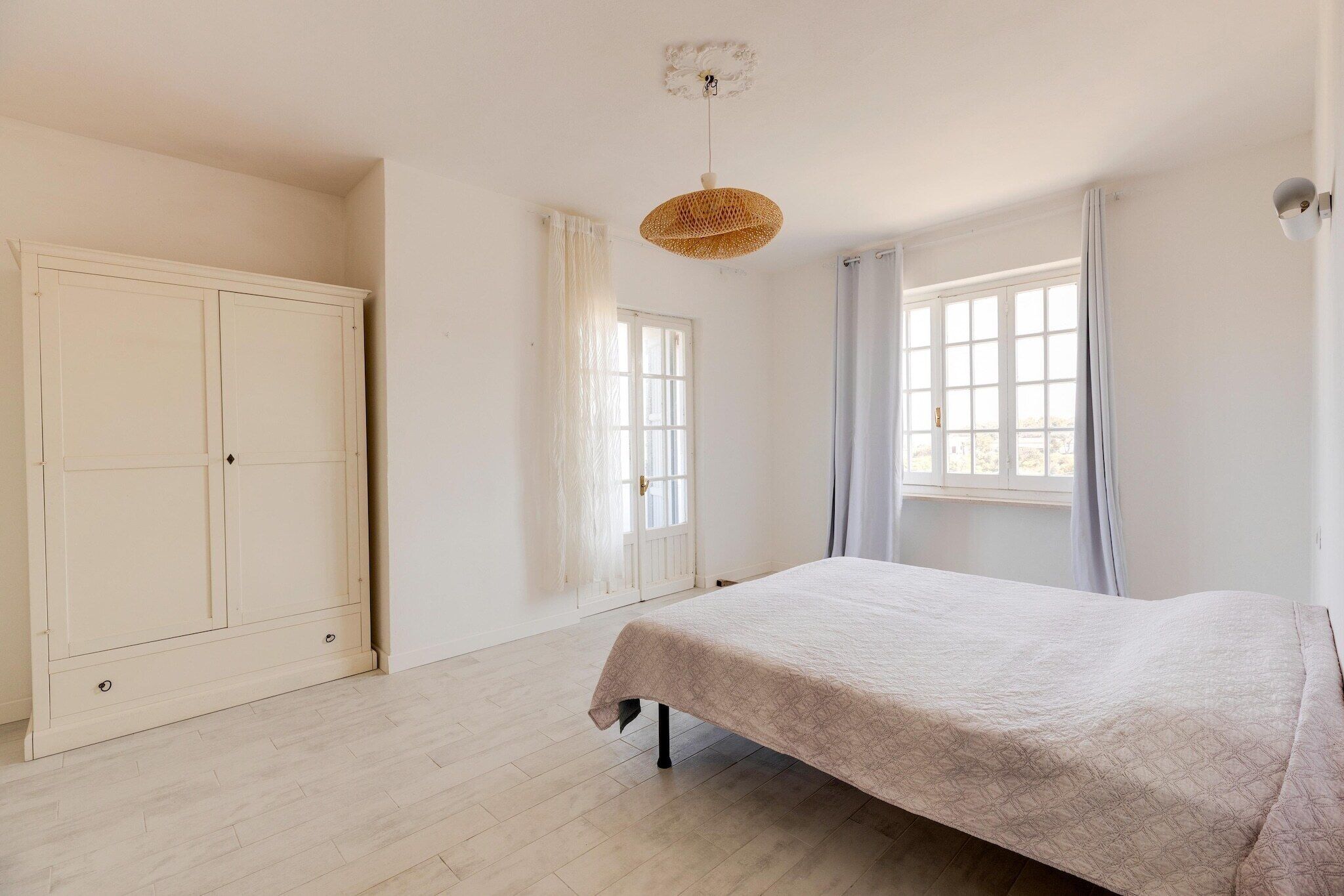 A bedroom with a bed, a wardrobe, and a window with curtains.