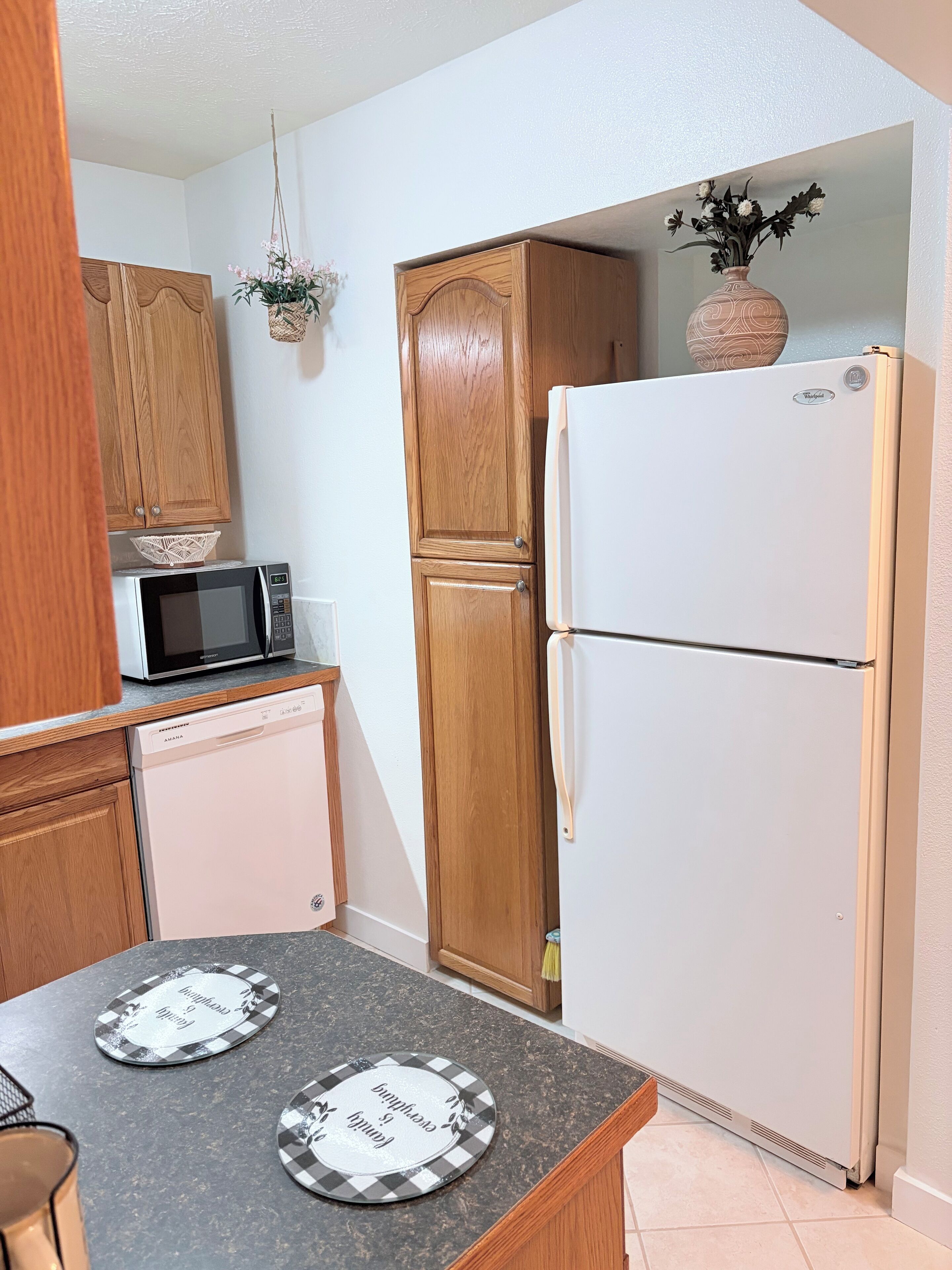 A kitchen with wooden cabinets, a microwave, a refrigerator, and two plates on the counter.