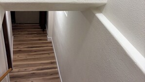 A wooden staircase with white walls and a textured ceiling.