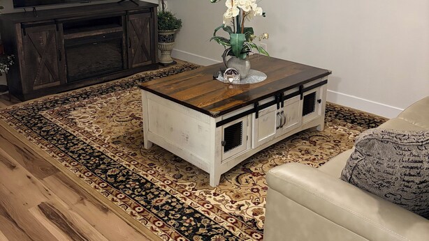 A living room with a wooden coffee table, a beige sofa, a TV, and a ceiling fan.