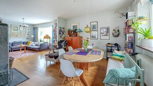 Ein gemütliches Wohnzimmer mit einer Couch, einem Esstisch mit Stühlen und einem Bücherregal voller Bücher und Dekoration.