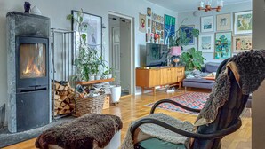 Ein gemütliches Wohnzimmer mit Kamin, bequemen Sesseln, einer Couch und einem Essbereich mit Holzschrank und Fernseher.