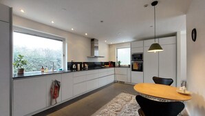 Une cuisine moderne avec une grande fenêtre, un coin repas doté d’une table ronde et d’une chaise noire.