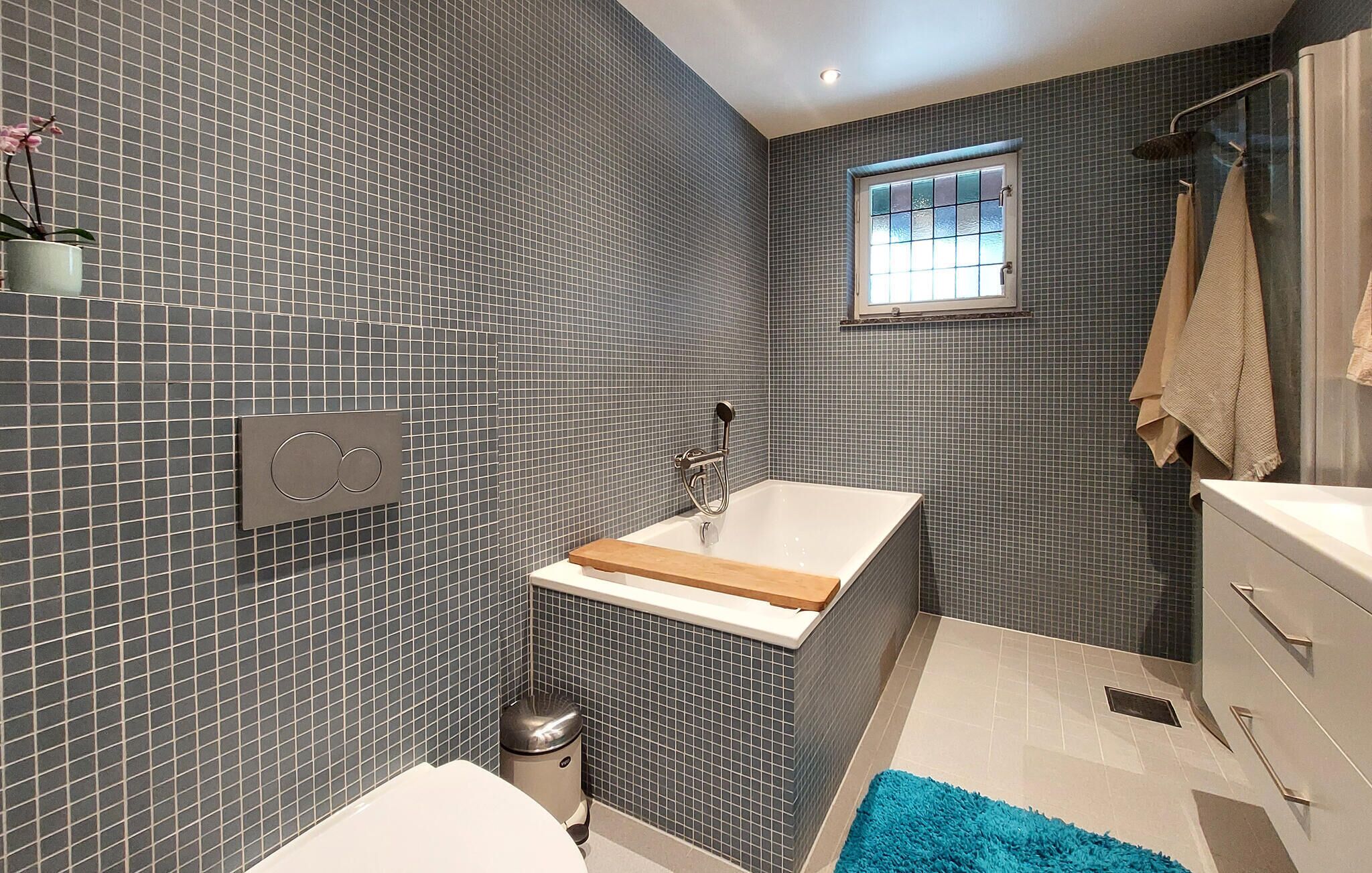 A modern bathroom with a bathtub, a toilet, and a window.