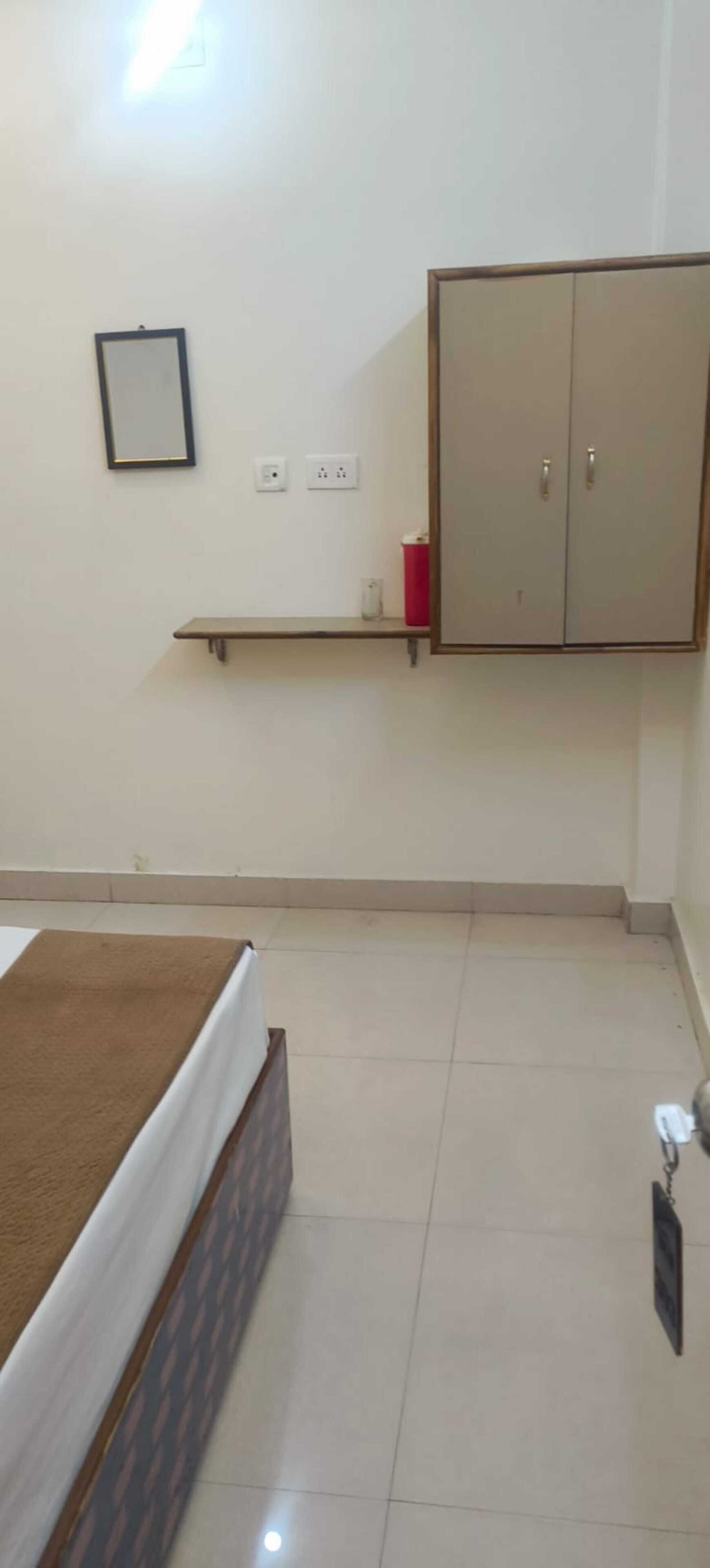 A bedroom with a bed, a wardrobe, a shelf, and a bedside table.