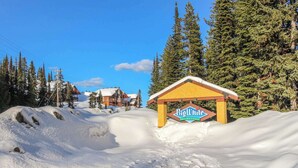 A Big White Ski Resort sign in a snowy landscape with buildings and trees. - Okanagan - Arolla Chalet D (Big White Mountain)
