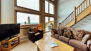 A living room with a TV, leather sofa, and a coffee table. - Okanagan - Arolla Chalet D (Big White Mountain)