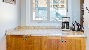 A kitchen with a granite countertop, wooden cabinets, a coffee maker, and a kettle. - Okanagan - Aspens Townhouse 1 (Big White Mountain)