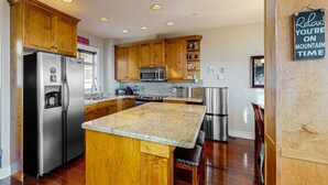 A kitchen with wooden cabinets, stainless steel appliances, granite countertops, and a sign that reads "Relax! You're on Mountain Time." - Okanagan - Aspens Townhouse 1 (Big White Mountain)
