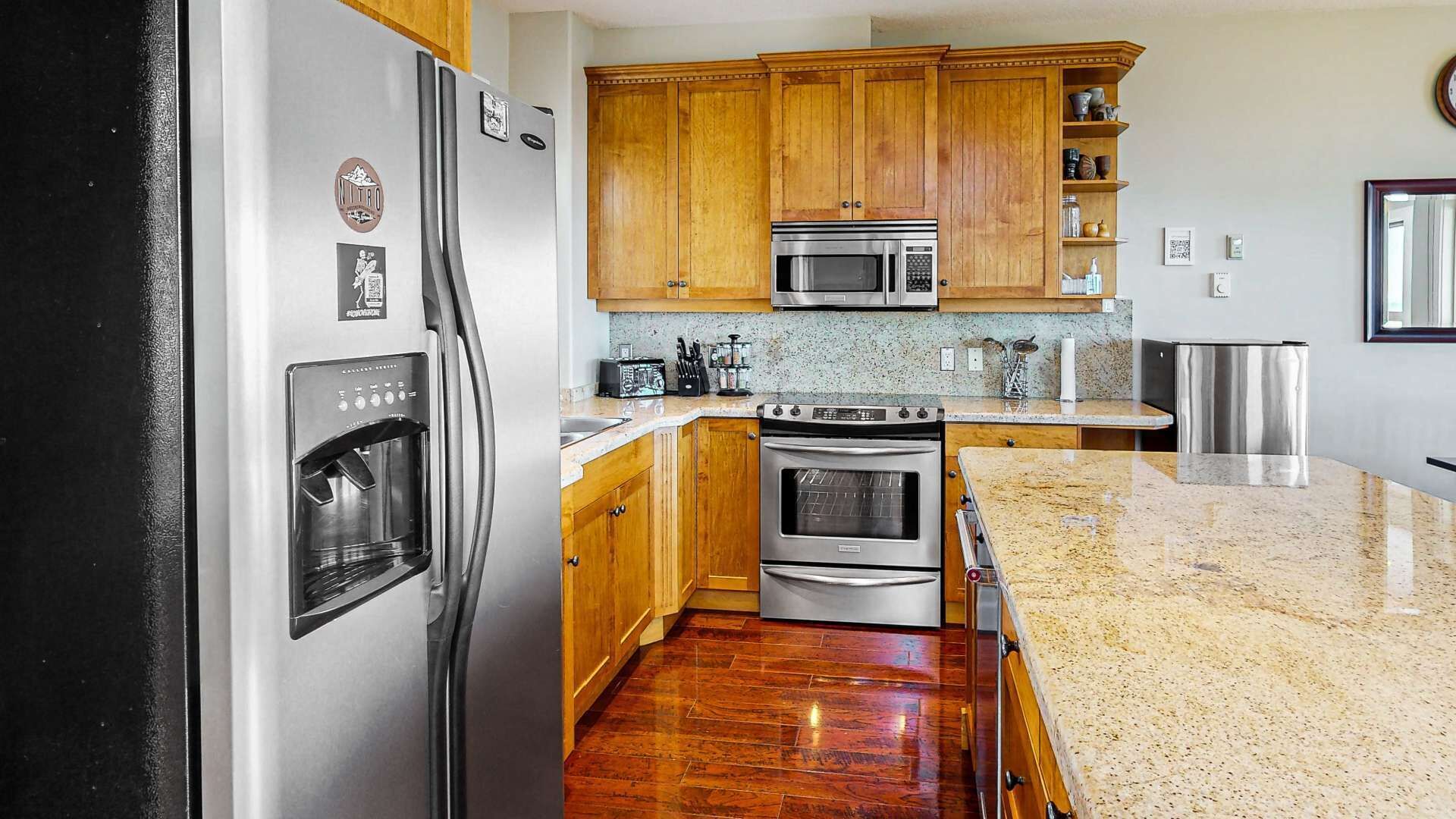 A kitchen with wooden cabinets, stainless steel appliances, granite countertops, and a built-in oven.