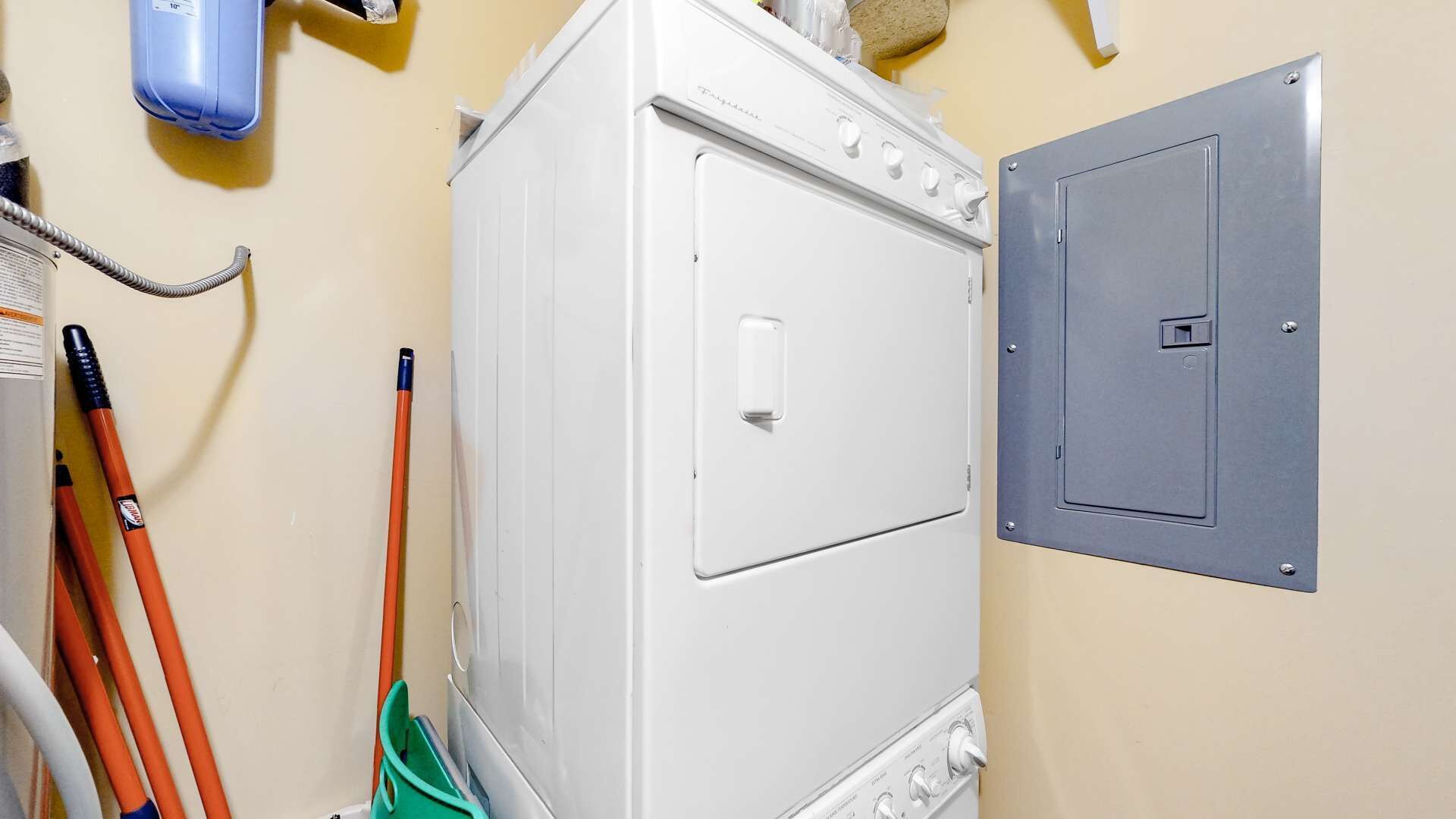 Una sala de bugaderia amb una rentadora blanca, una porta metàl·lica de servei i eines de neteja.