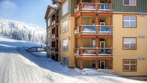 A multi-story lodge with balconies, a ski lift in the background, and a snowy landscape. - Okanagan - Aspens 4307 (Big White Mountain)