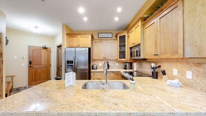 A kitchen with granite countertops, stainless steel appliances, wooden cabinets, and a built-in microwave. - Okanagan - Aspens 4307 (Big White Mountain)