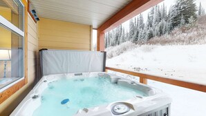 Een bubbelbad met uitzicht op een besneeuwd bos.