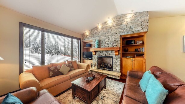 Un salón acogedor con chimenea de piedra, sofás de cuero y una televisión.