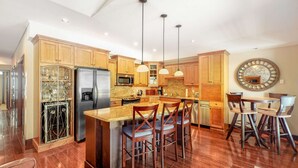 Una cocina amplia con armarios de madera, electrodomésticos de acero inoxidable y una isla central con taburetes de bar.