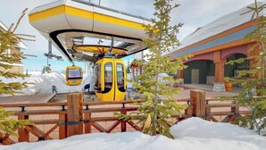 Eine gelbe Kabse gondelt an einer Station mit einem hölzernen Zaun und schneebedecktem Boden.