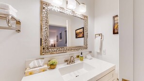 A bathroom with a white sink, a large mirror with a decorative frame, a towel rack, and a small potted plant. - Okanagan - Brooks Lake House (Christina Lake)