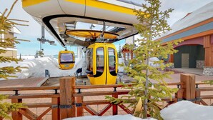 A yellow cable car at a station with a wooden fence and snow-covered ground. - Okanagan - Glacier Lodge 103 (Beaverdell)