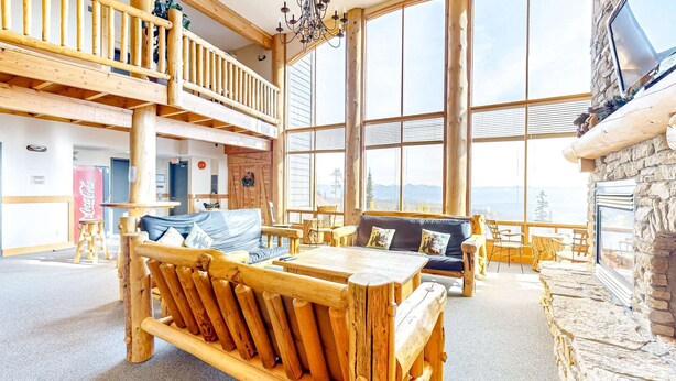 A spacious lodge with a high ceiling, wooden furniture, and large windows offering mountain views. - Okanagan - Grizzly Lodge 306 (Beaverdell)