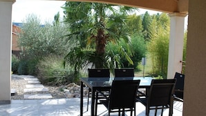 An outdoor patio with a table and chairs, surrounded by greenery and a palm tree. - Blue Hills Residence with Scenic Views (Sampzon)